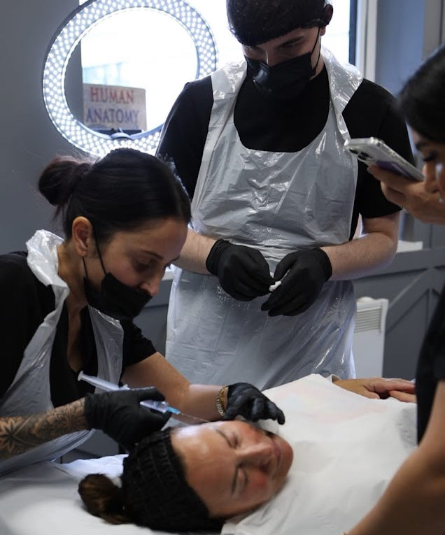 Person receiving a facial treatment in a clinical setting with medical professionals.